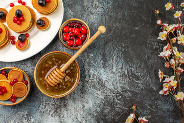 Half shot of classic pancakes on wooden cutting board honey in a bowl and flowers on gray table