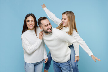 Cheerful young parents mom dad with child kid daughter teen girl in white sweaters giving piggyback...