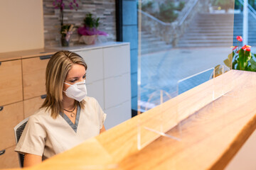 receptionist from the physiotherapy center behind desk with pandemic mask