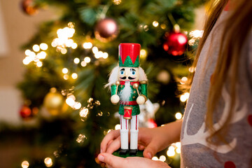 Close-up of children girl holding wooden nutcracker toy in hands. Christmas decoration symbol