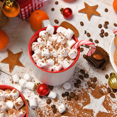 sweet food top view background for merry christmas or new year holiday decoration - chocolate candies, tangerines, cookies, marshmallow and cocoa latte on white wood