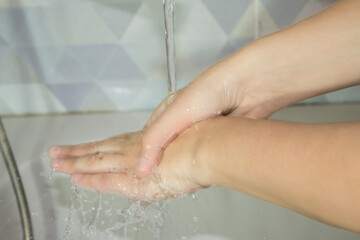 To wash hands. Wash your hands under the tap. Female hands close-up under running water in the bathroom. Hygiene, cleanliness, coronavirus, virus, health, medicine