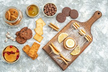 Simple pancakes with lemons on cutting board and chocolate cookies honey on blue background