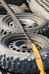 A set of spare wheels for a rally car, lying on the trailer and wrapped with a belt