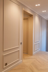 Modern and bright interior of an empty cream colored corridor with a herringbone parquet floor