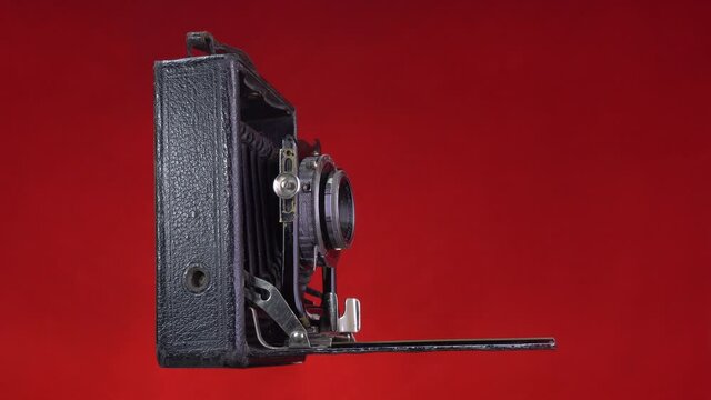 Timelapse  old antique photo camera shooting. Isolated on red background. Vintage object.