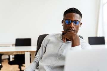 Afro american serious man in earphones working with laptop