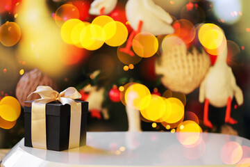 new year lights glow brightly with the rays from the garland. background texture of Christmas lights on a holiday tree. make a wish. black gift box with a bow.