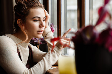 Young caucasian beautiful woman drawing on window glass indoors