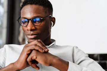 Afro american young man in eyeglasses working with laptop indoors