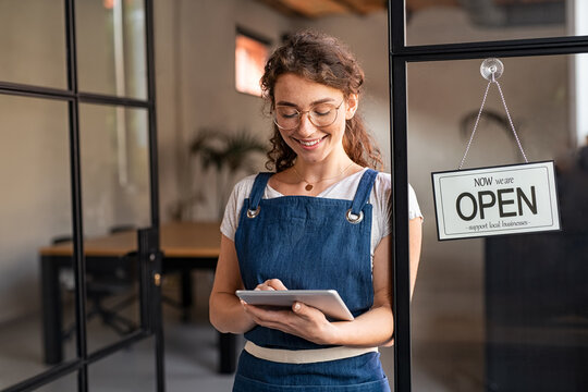 Small business owner using digital tablet at entrance