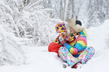 Fototapeta na wymiar little girl and mother sit and play in the snow in the park