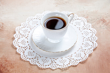 Close up view of a cup of black tea on a white decorated napkin on colourful background
