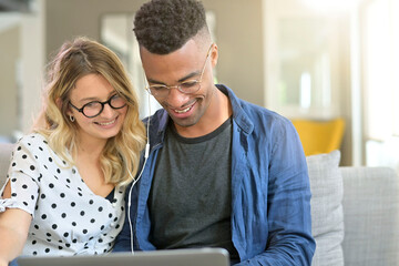 Mixed-raced couple connected together on laptop at home