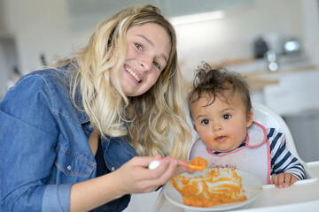 Obraz na płótnie Canvas Mom feeding 8-month-old baby girl