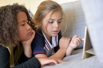 10-year-old girlfriends watching movie on digital tablet