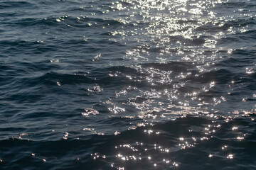 Blue sea with sunny glare on the surface with blurry background, used as a background or texture,...