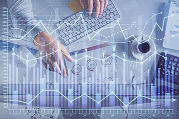 Multi exposure of man's hands typing over computer keyboard and forex graph hologram drawing. Top view. Financial markets concept.