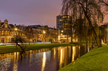 Fototapeta na wymiar Rotterdam, The Netherlands, December 13, 2020: historic houses and a more recent apartment tower along Noordsingel canal during the blue hour