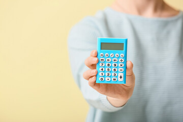 Woman with calculator on color background, closeup