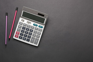 Modern calculator and pencils on dark background