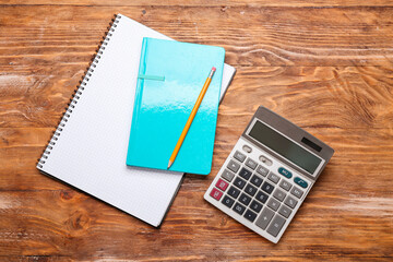 Modern calculator and stationery on wooden background