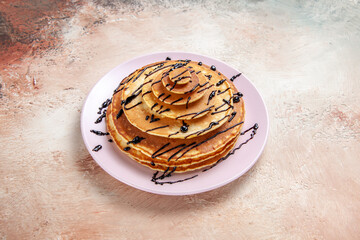 Top view of homemade pancakes decorated with chocolate syrup on a white background