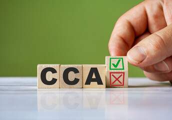 The hand turn wooden block with red reject X and green confirm tick as change concept of CCA. Word...