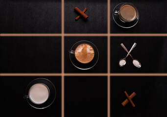 Cappuccino coffee with milk; game tic tac toe on a black background table