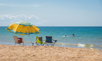 Bright marine umbrella with chairs on the beach against the background of the sea.