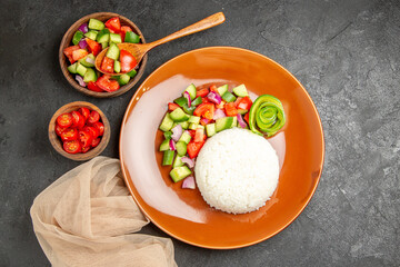 Overhead view of vegan dinner with rice and different types of vegetables on dark background