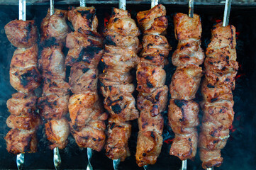 pork kebab on skewers is grilled over charcoal, smoke over a barbecue, the last degree of cooking, close