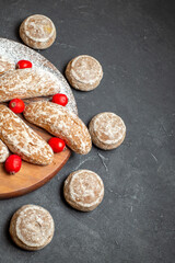 Top view of tasty cookies and red cornel berries on dark background