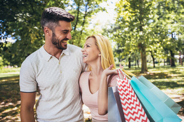 Happy couple carrying shopping bags and enjoying together on summer day.