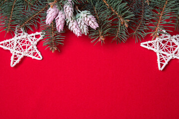 Layout for Christmas decorations or flatlays with spruce branches on a red background