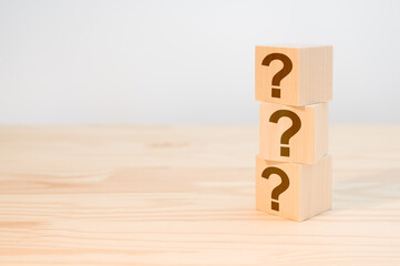 Wooden cube block shape with sign question mark symbol on wood table. column of wooden blocks with...