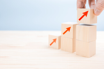 Close up Businessman hand arranging wood cube with arrow stacking as step stair. business growth success process concept