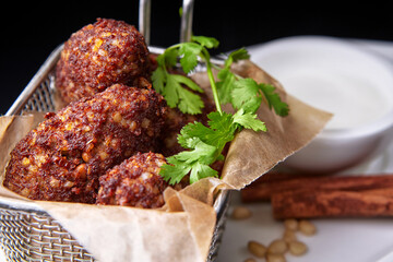 Chickpea falafel with sauce and cinnamon sticks, on a white plate
