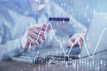 Double exposure of man hands holding a credit card and Forex graph drawing. Stock trading and digital fintech in Internet E-commerce concept.