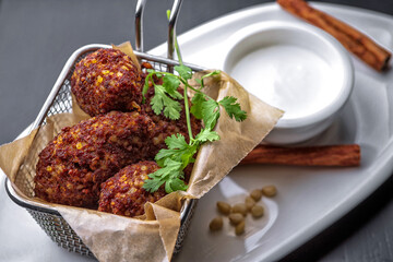Chickpea falafel with sauce and cinnamon sticks, on a white plate
