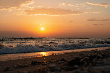 Colorful sunset on a sandy beach, waves with foam on the sand. Ocean, coast. Soft selective focus.
