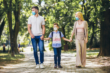 Mother,father and little son wearing face protective medical mask for protection from virus disease in park.