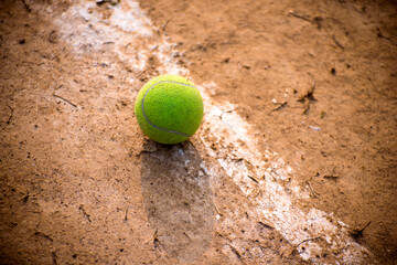 Close-up of tennis ball on clay court on the side line.