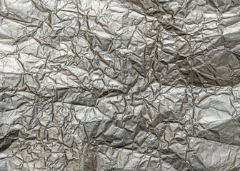 Wrinkled metal foil texture, silver color, grunge abstract background.