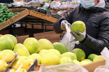 Fototapeta premium A young woman wearing protective gloves buys food at a store during the coronavirus epidemic.