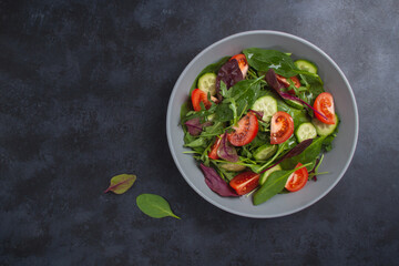 Fototapeta na wymiar Healthy fresh salad of vegetable cucumber, tomato, spinach, arugula