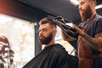 Male barber drying hair of hipster