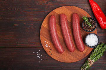 Raw meat beef sausages for grill and spicy, herbs rosemary, pepper, salt on table