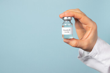 A doctor or laboratory technician holds a vial with a hepatitis B vaccine in his hand. With a place...