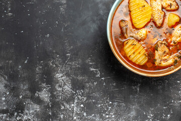 Tomato chicken soup on the right bottom corner on dark background